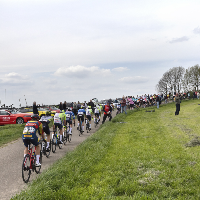 Amstel Gold Race 2024 - Riders pass team cars lined up on the crest of a climb on Schaapsdries
