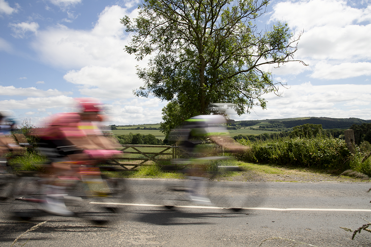 British National Road Championships 2024 - Men’s Road Race - The peloton speeds past a five bar gate and open countryside in Upleatham