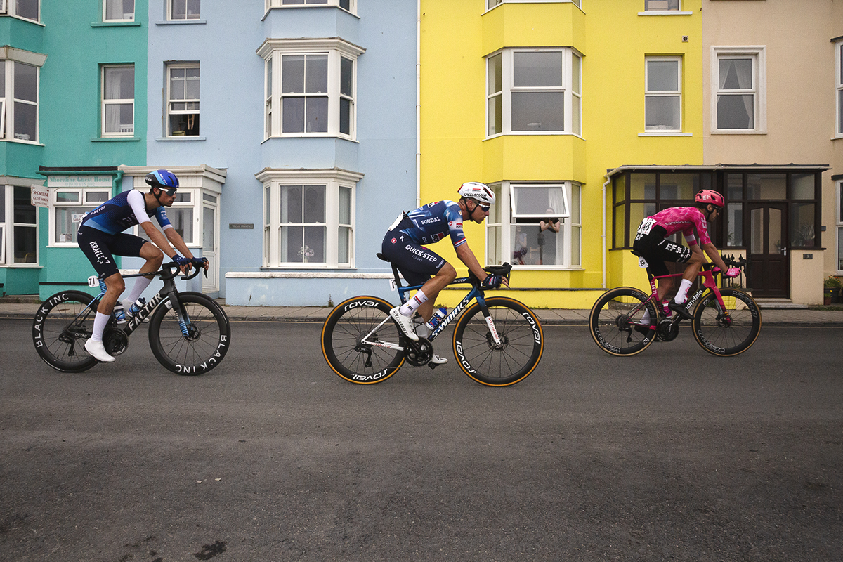 British National Road Championships 2025 - Road Race - Men - Road Race - Men - a small group of riders pass by colourful houses in Aberystwyth