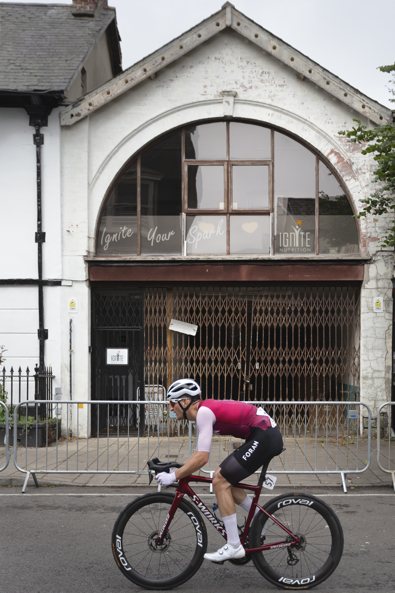 British National Road Championships 2025 - Road Race - Men - Danylo Riwnyj of Foran CT races past a building with an archway