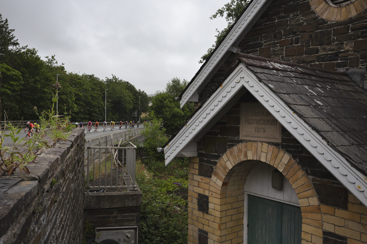 British National Road Championships 2025 - Road Race - Men - riders are strung out on the road in Llanfarian as they pass close to a small chapel