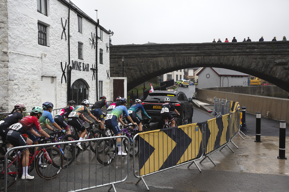British National Road Championships 2025 - Road Race - Women - Aberystwyth - the peloton rolls out past a whitewashed wine bar under a bridge