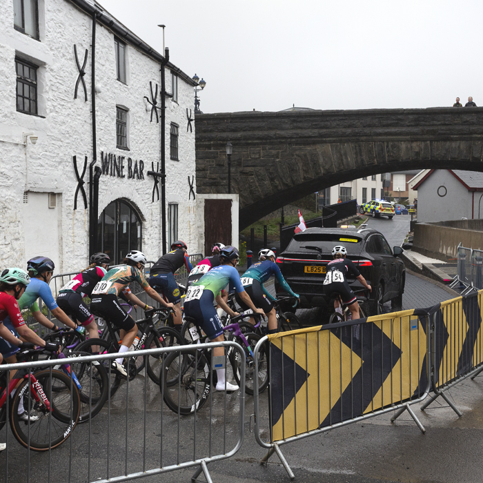 British National Road Championships 2025 - Road Race - Women - Aberystwyth - the peloton rolls out past a whitewashed wine bar under a bridge
