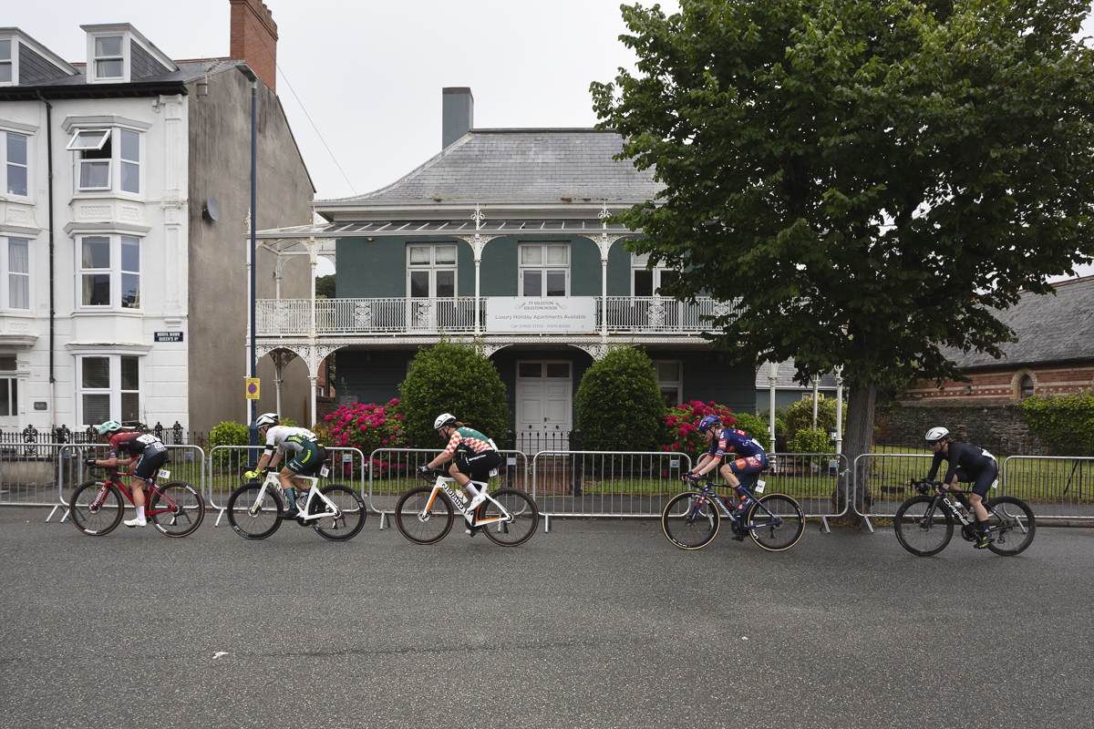 British National Road Championships 2025 - Road Race - Women - Aberystwyth - a group of riders pass a colonial looking house