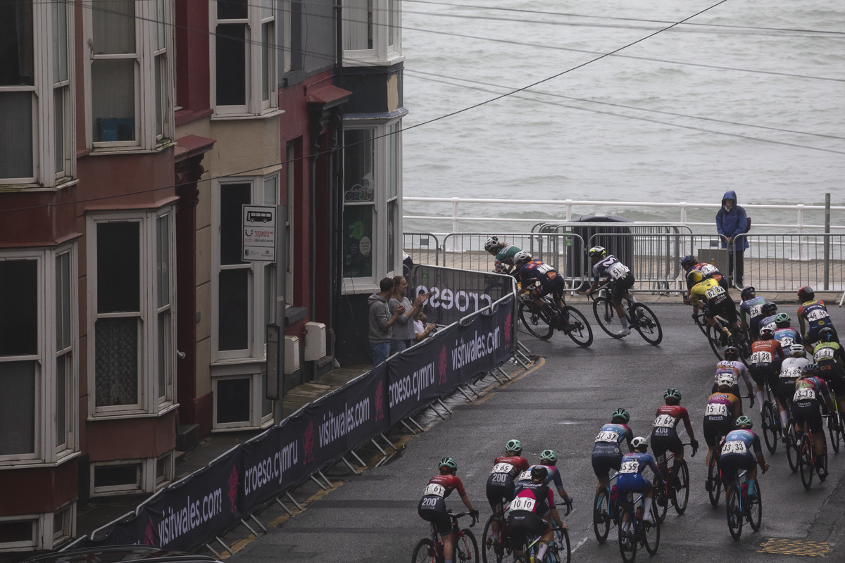 British National Road Championships 2025 - Road Race - Women - Aberystwyth - riders take a corner onto the seafront with guesthouses to the side