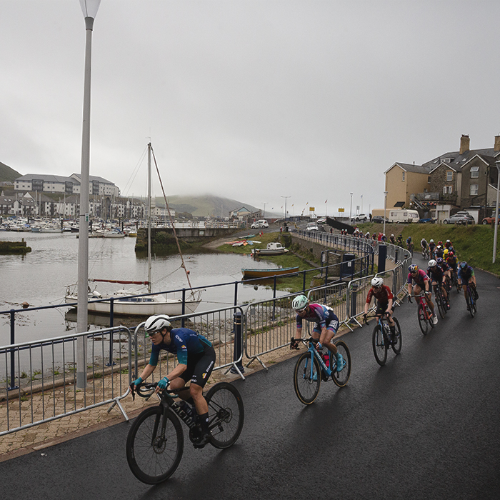 British National Road Championships 2025 - Road Race - Women - Aberystwyth - riders pass the old harbour with boats bobbing on the water