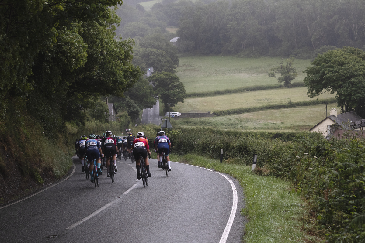British National Road Championships 2025 - Road Race - Women - Rhydyfelin - a rear view of riders with the road stretching out in front and a view over the fields to one side