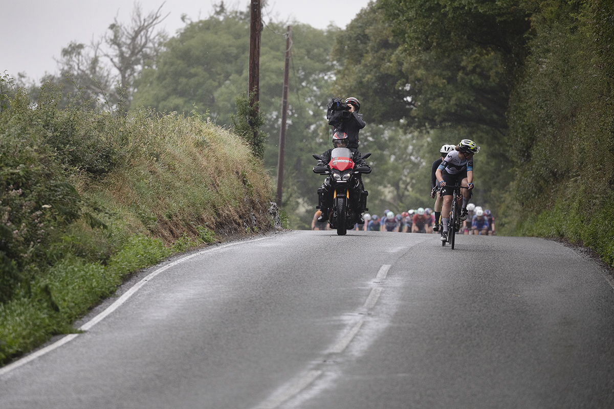 British National Road Championships 2025 - Road Race - Women - Rhydyfelin a Movistar rider looks behind at the peloton just cresting a rise behind her