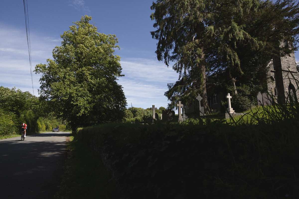 British National Road Championships 2025 - Time Trial - Elite Men - Connor Swift passes by a small cemetery during the event