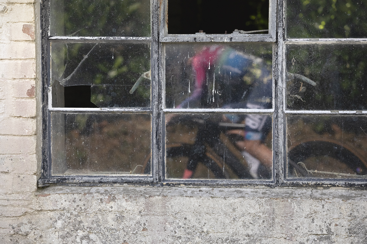British National Road Championships 2025 - Time Trial - Elite Women - a reflection of one of the competitors in the window of a disused barn