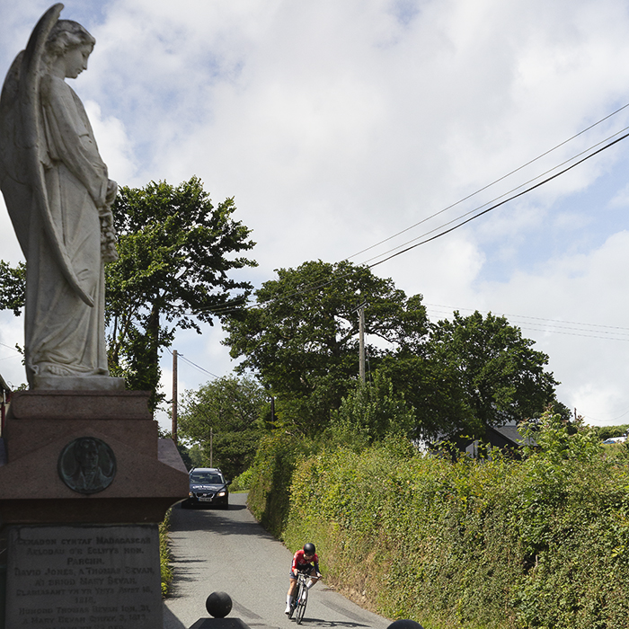 British National Road Championships 2025 - Time Trial - Elite Women - Lucy Gadd of Smurfit Westrock Cycling Team rides past a large statue of an angel in the grounds of a local chapel