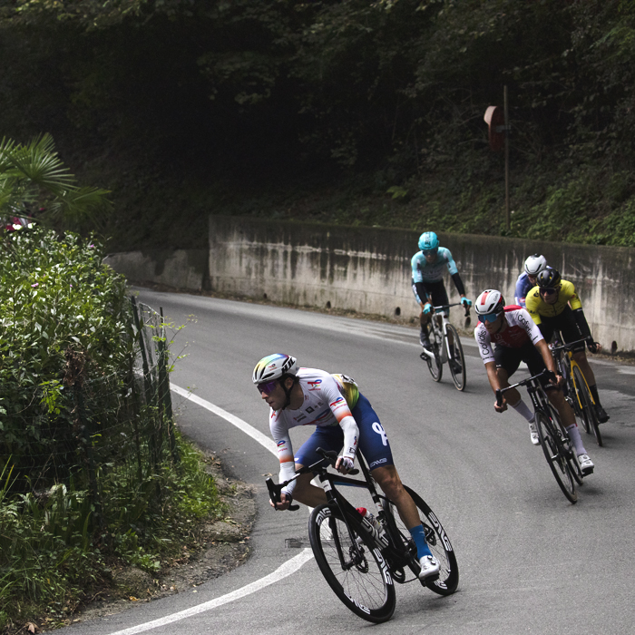 Coppa Bernocchi 2024 - Riders take on a sharp bend near a lush garden in Castelseprio