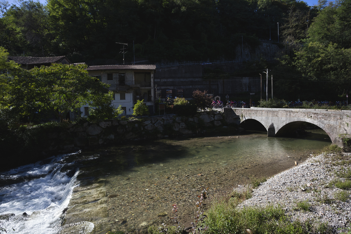 Coppa Bernocchi 2025 -Riders pass down the riverfront near an historic bridge in Castiglione Olona