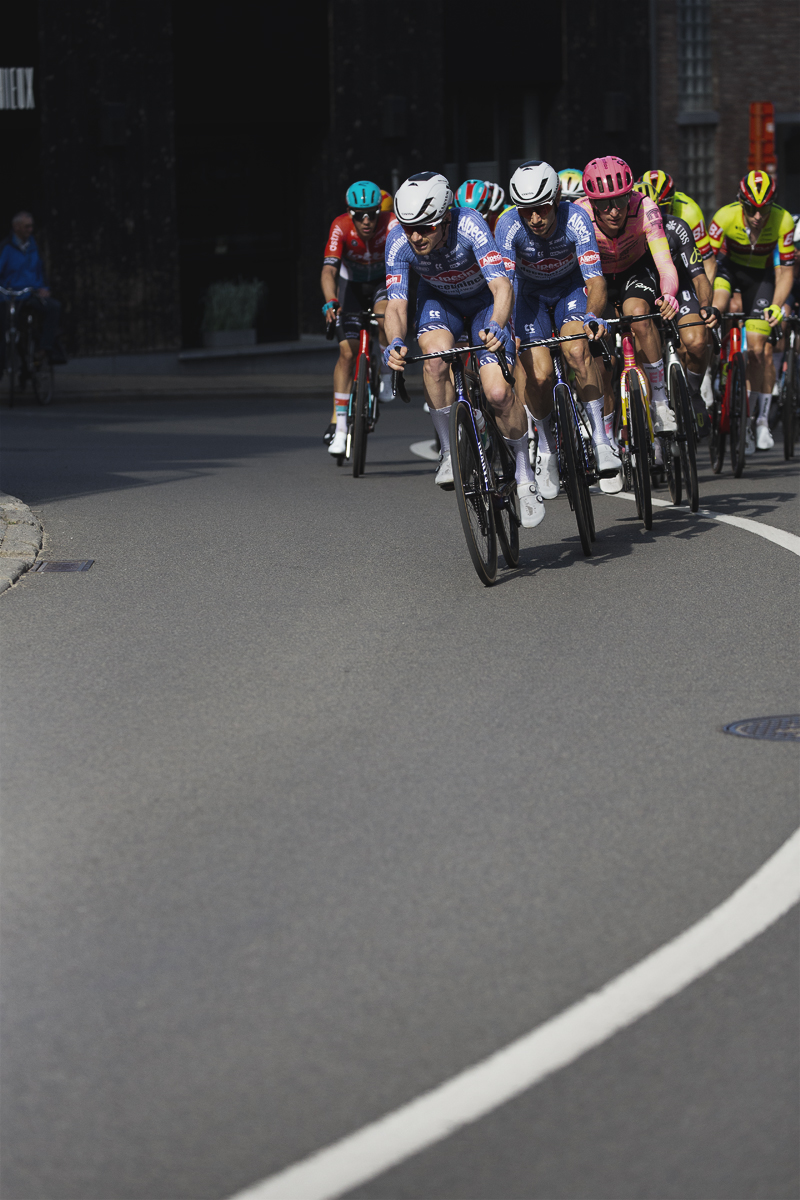 De Brabantse Pijl 2024 - Alpecin - Deceuninck lead riders round the curve of a bend in Overisje