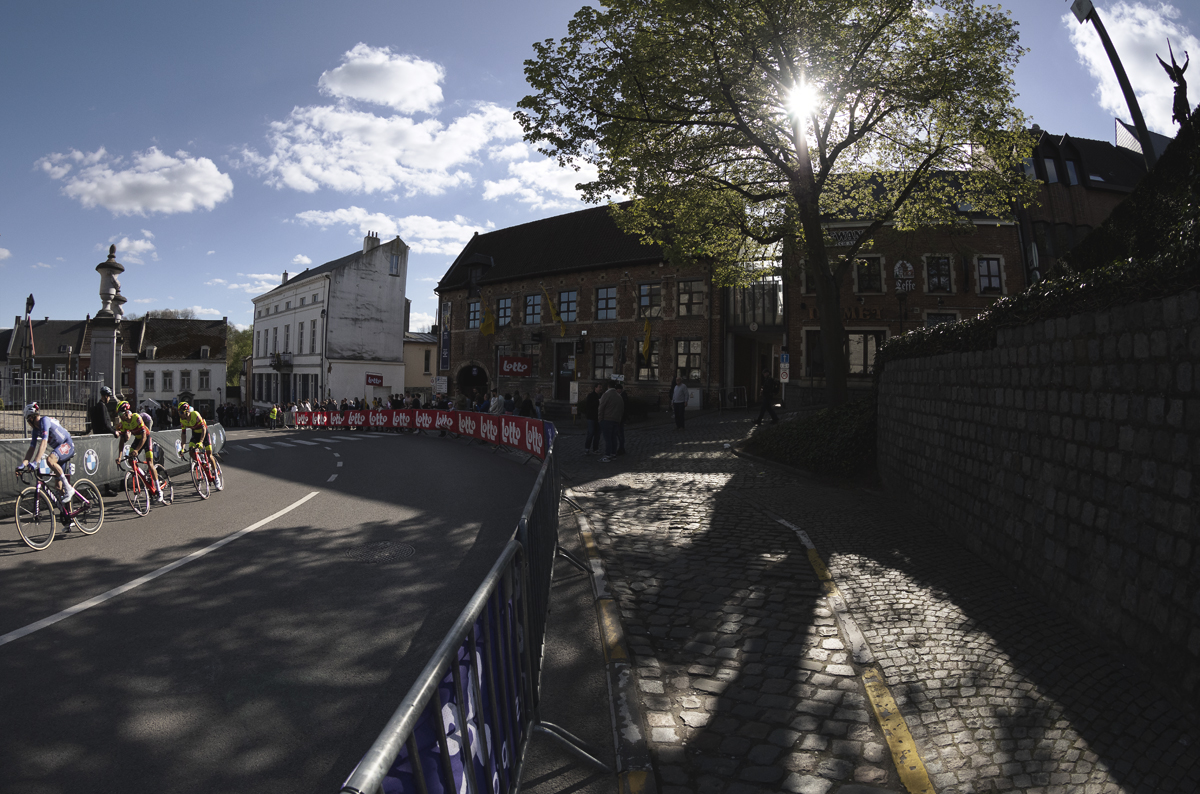 De Brabantse Pijl 2024 - Sun shines through a tree on Justus Lipsiusplein as the riders pass by