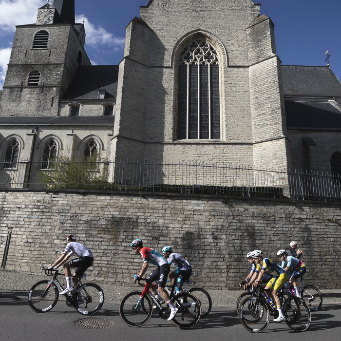 De Brabantse Pijl 2024 - A small group of riders pass Sint-Martinus Kerk which towers above the road