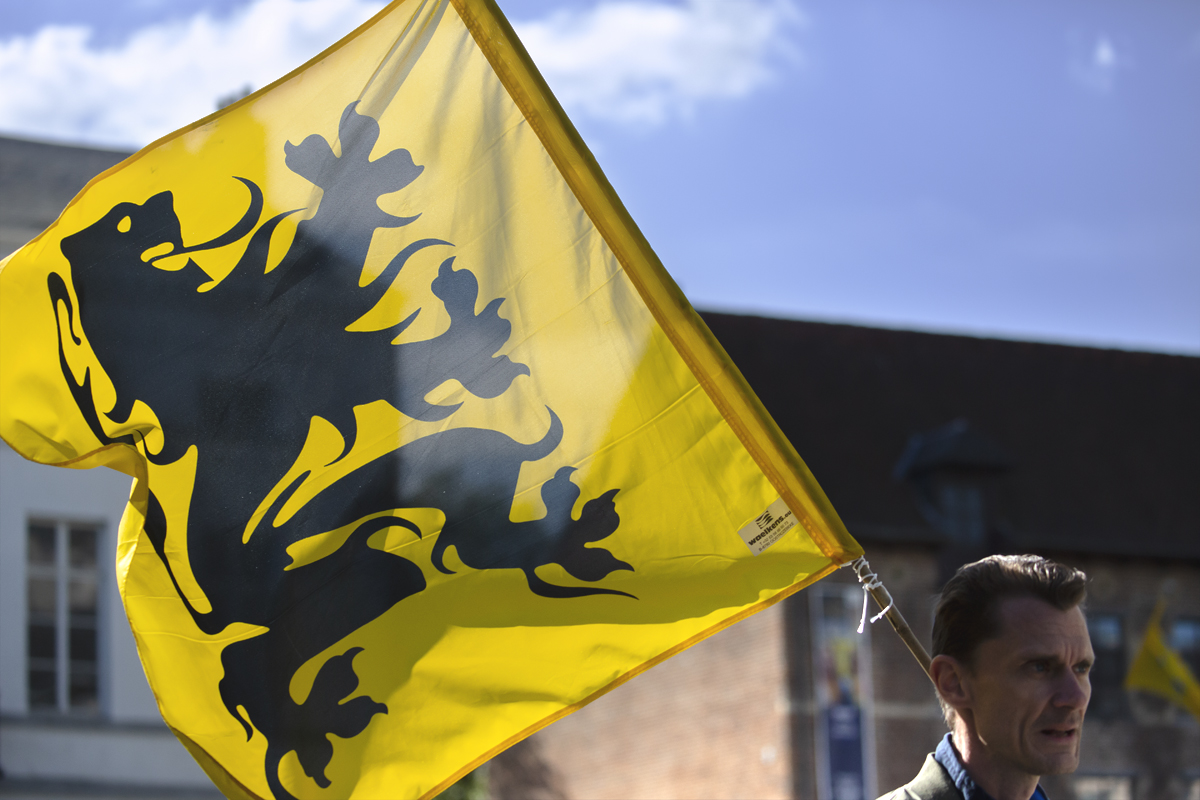 De Brabantse Pijl 2024 - The yellow flag of Flanders with its rampant black lion is held aloft in the light