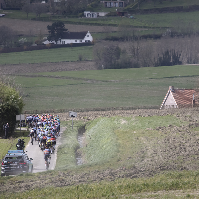 Dwars Door Vlaanderen 2024 - Riders with ploughed fields and a high bank next to them on Rue des Chapelles