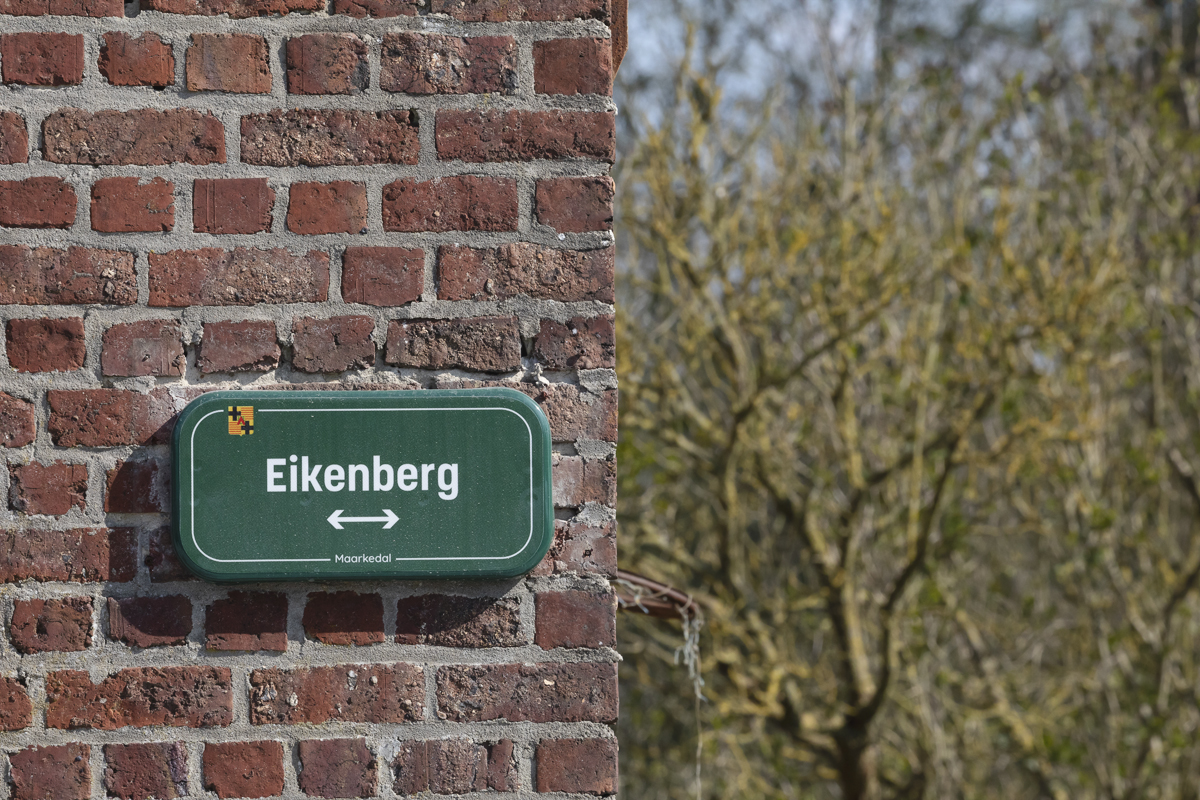 Dwars Door Vlaanderen 2025 - A green sign on a brick wall reads Eikenberg