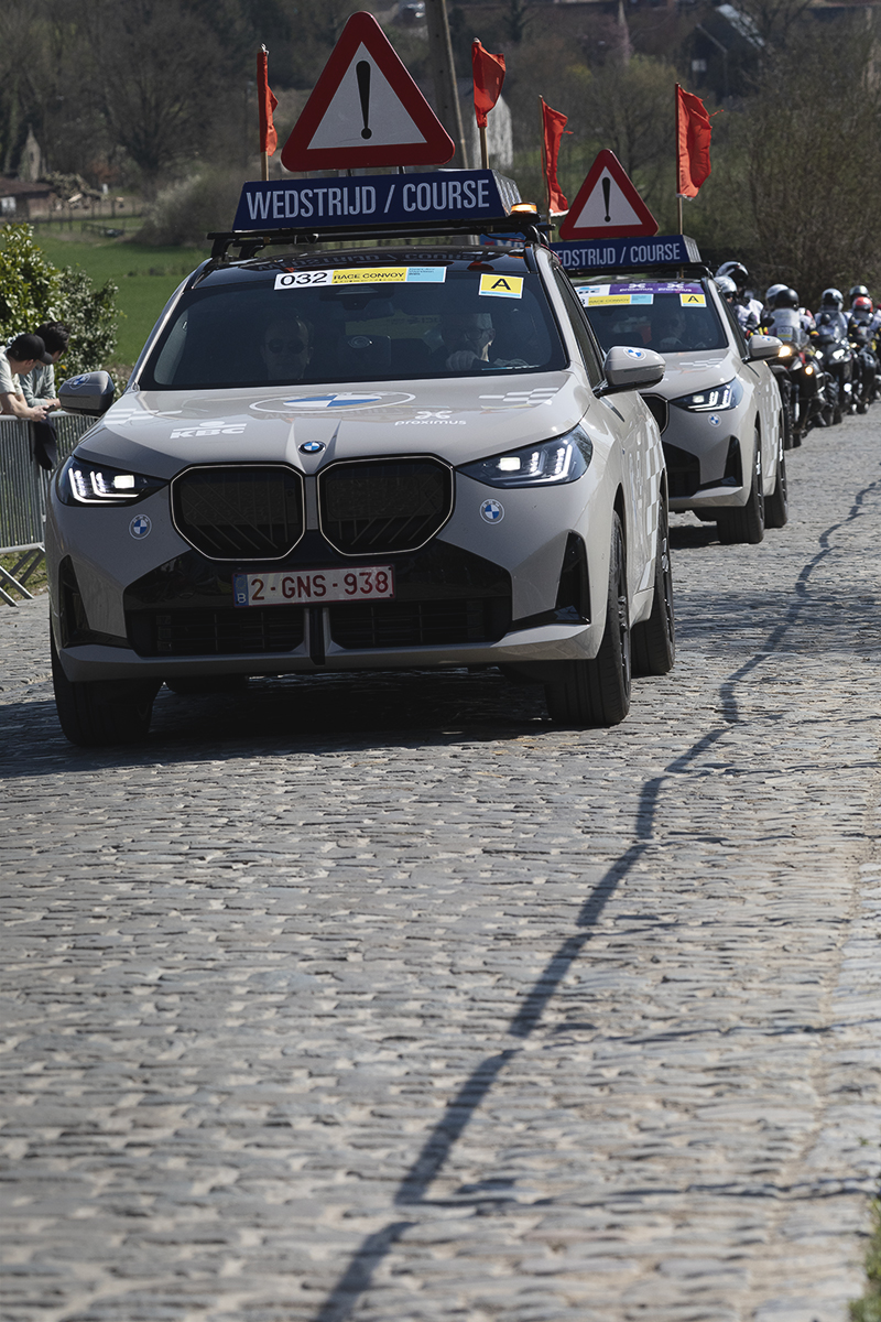 Dwars Door Vlaanderen 2025 - A convoy of race traffic makes its way up Eikenberg