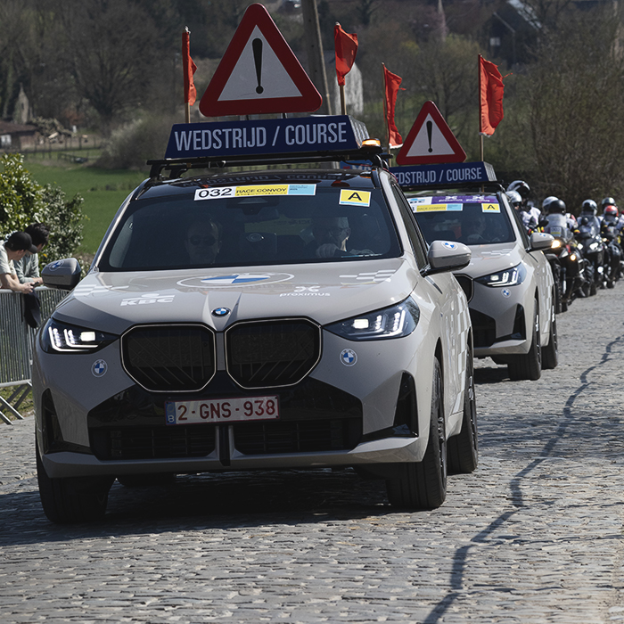 Dwars Door Vlaanderen 2025 - A convoy of race traffic makes its way up Eikenberg