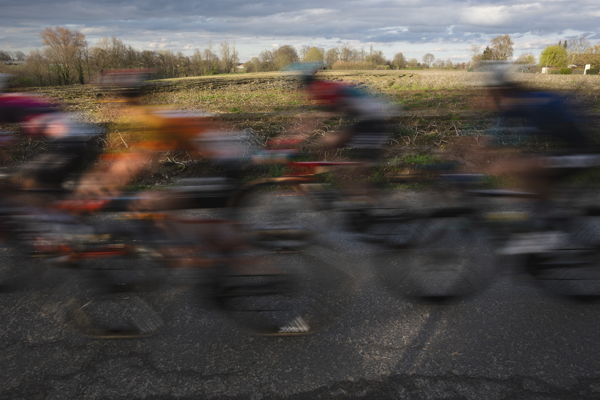 Dwars Door Vlaanderen Vrouwen 2024 - Riders speed past open fields during the race