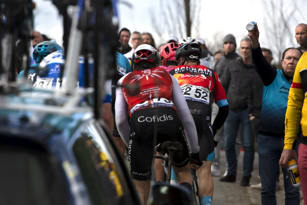 E3 Saxo Classic 2023 - Soigneurs hold up bidons for approaching riders on Mariaborrestraat