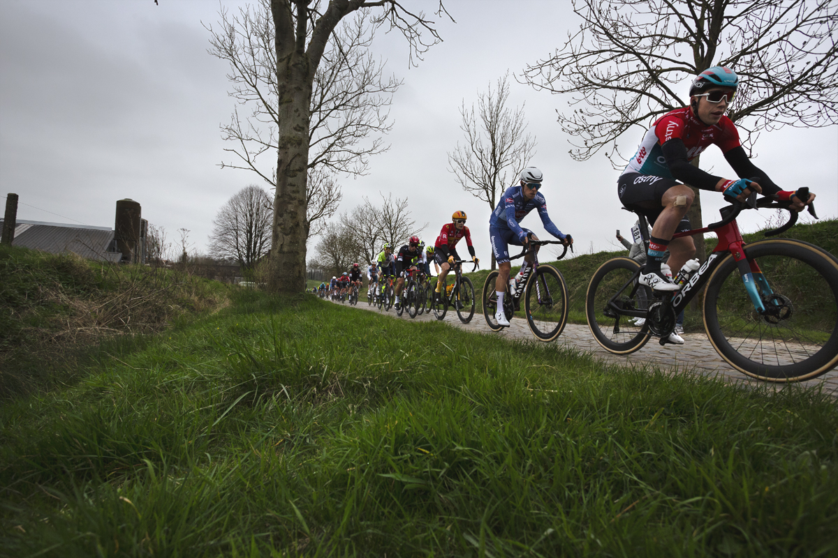 E3 Saxo Classic 2024 - A strung out group of riders tackle the cobbled road of Paddestraat