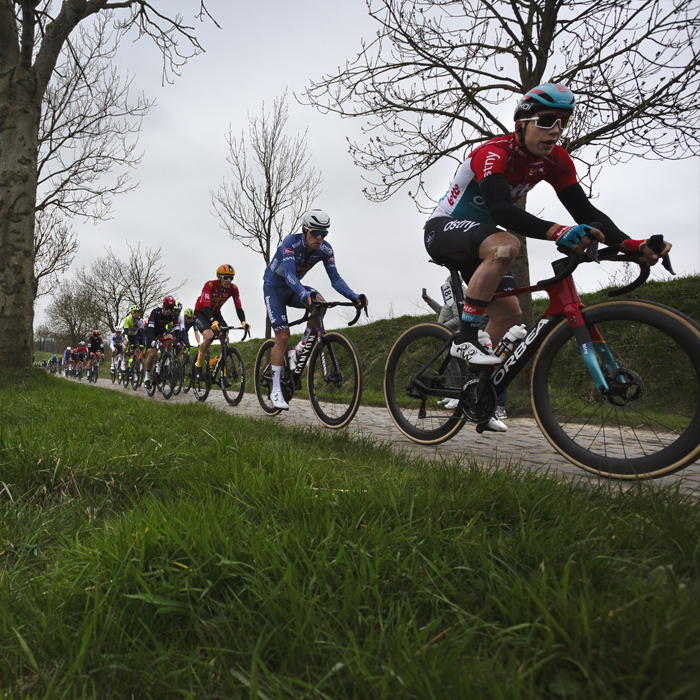 E3 Saxo Classic 2024 - A strung out group of riders tackle the cobbled road of Paddestraat