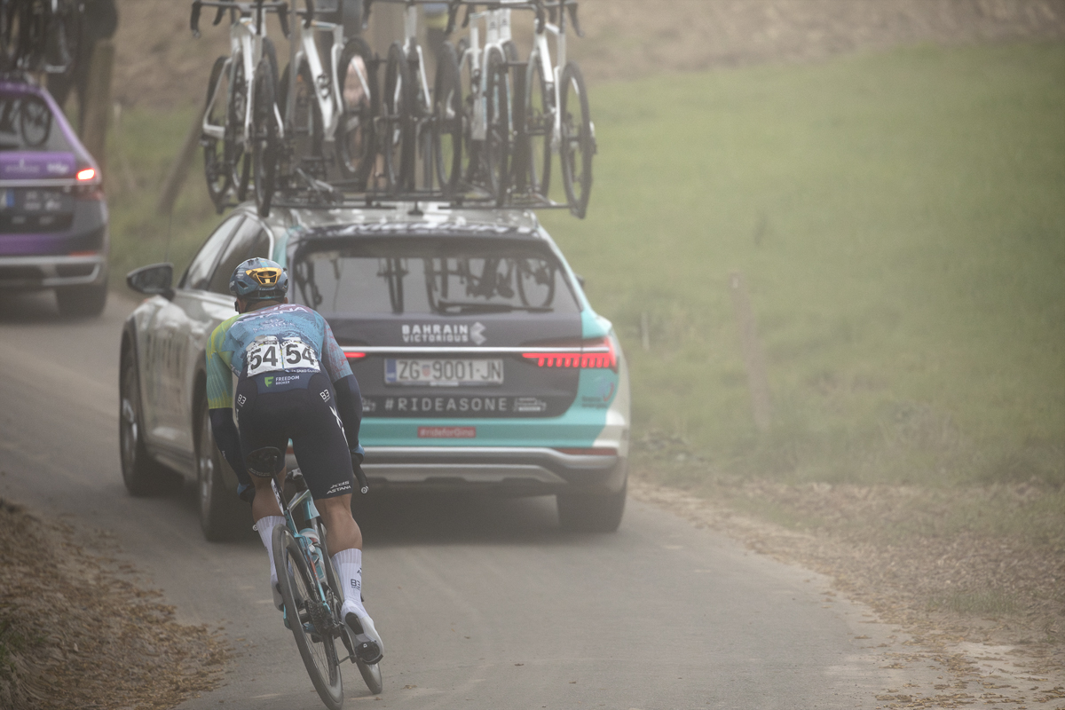 E3 Saxo Classic 2025 - A team car kicks up dust as  Matteo Malucelli follows it in an attempt to get back to the peloton