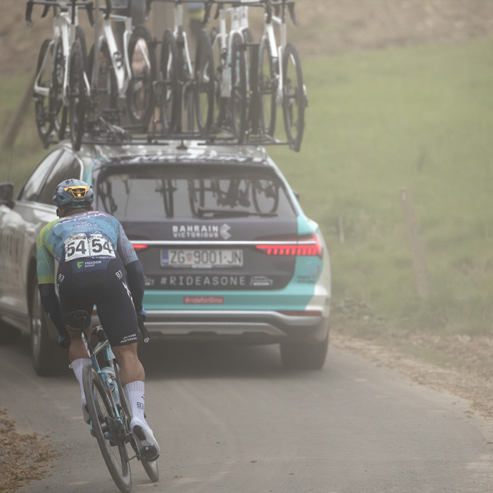 E3 Saxo Classic 2025 - A team car kicks up dust as  Matteo Malucelli follows it in an attempt to get back to the peloton