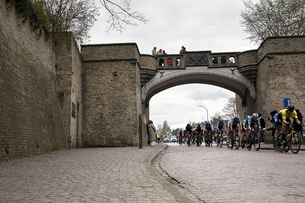 Gent Wevelgem 2024 - Riders pass through Rijselpoort while fans watch from a vantage point on top of the gateway