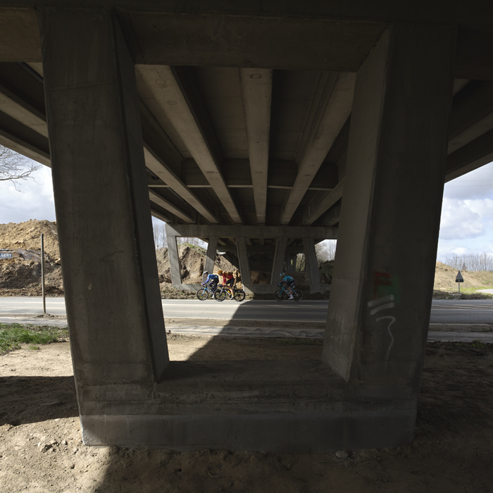 Gent Wevelgem 2024 - Riders pass under a modern bridge in Morsele