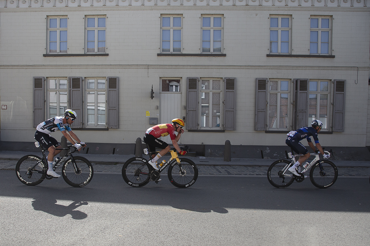 Gent Wevelgem 2025 - Manlio Moro, Anders Skaarseth and Cyril Barthe ride past a grand old building with shuttered windows.