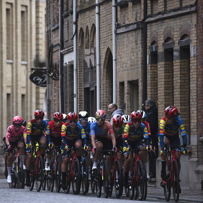 Gent Wevelgem Vrouwen 2024 - Riders on a street enclosed by tall brick buildings in Ieper / Ypres