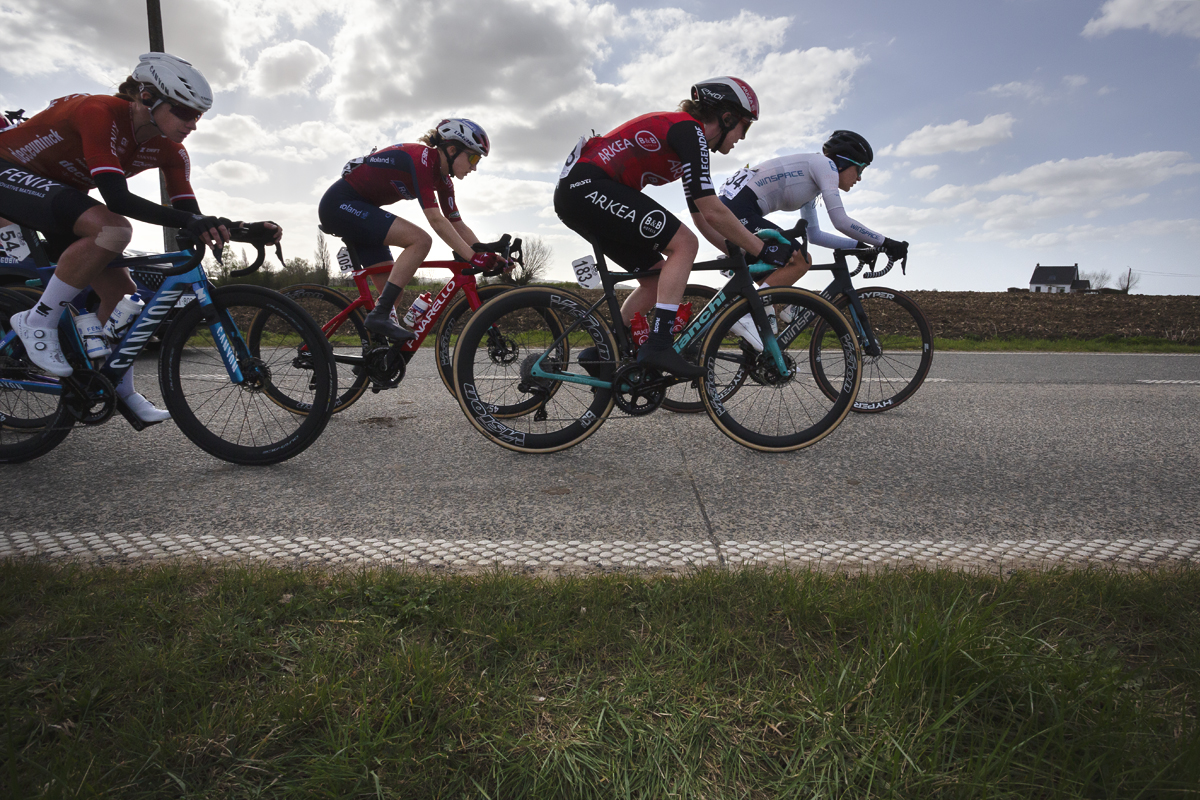 Gent Wevelgem Vrouwen 2025 - Riders in Loker with a small white cottage in the distance