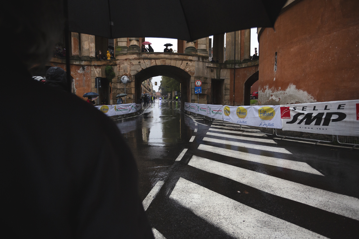 Giro dell’Emilia 2024 - Fans huddle under umbrellas waiting for the next pass of the race under the Arco Del Meloncello