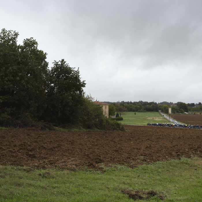 Giro dell’Emilia 2024 - The peloton in the distance with a runied farmhouse in the foreground in Castelvetro