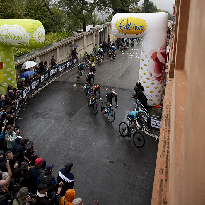 Giro dell’Emilia 2024 - Riders viewed from above pass by inflatable advertising arches as they take a corner on Via di San Luca