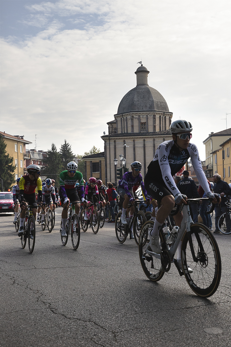 Giro dell’Emilia 2025 - The race rolls out of Mirandola against the backdrop of a domed church
