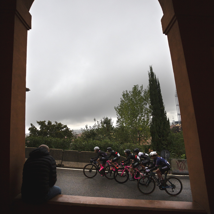 Giro dell'Emilia Internazionale Donne Elite 2024 - A fan sits in an archway in the portico watching a group of riders on the Via di San Luca