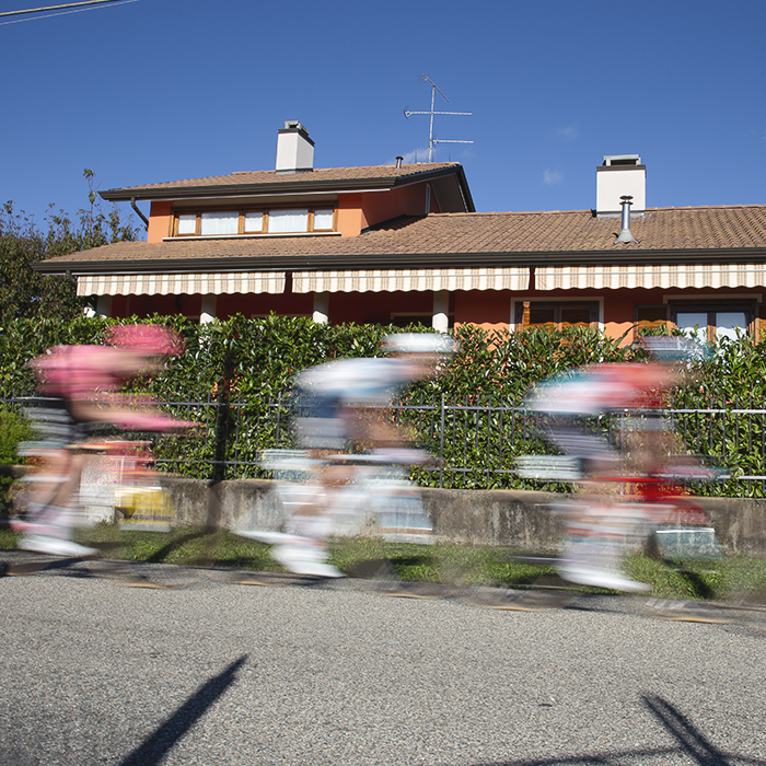Gran Piemonte 2024 - Riders speed past an orange coloured house in Maggiora