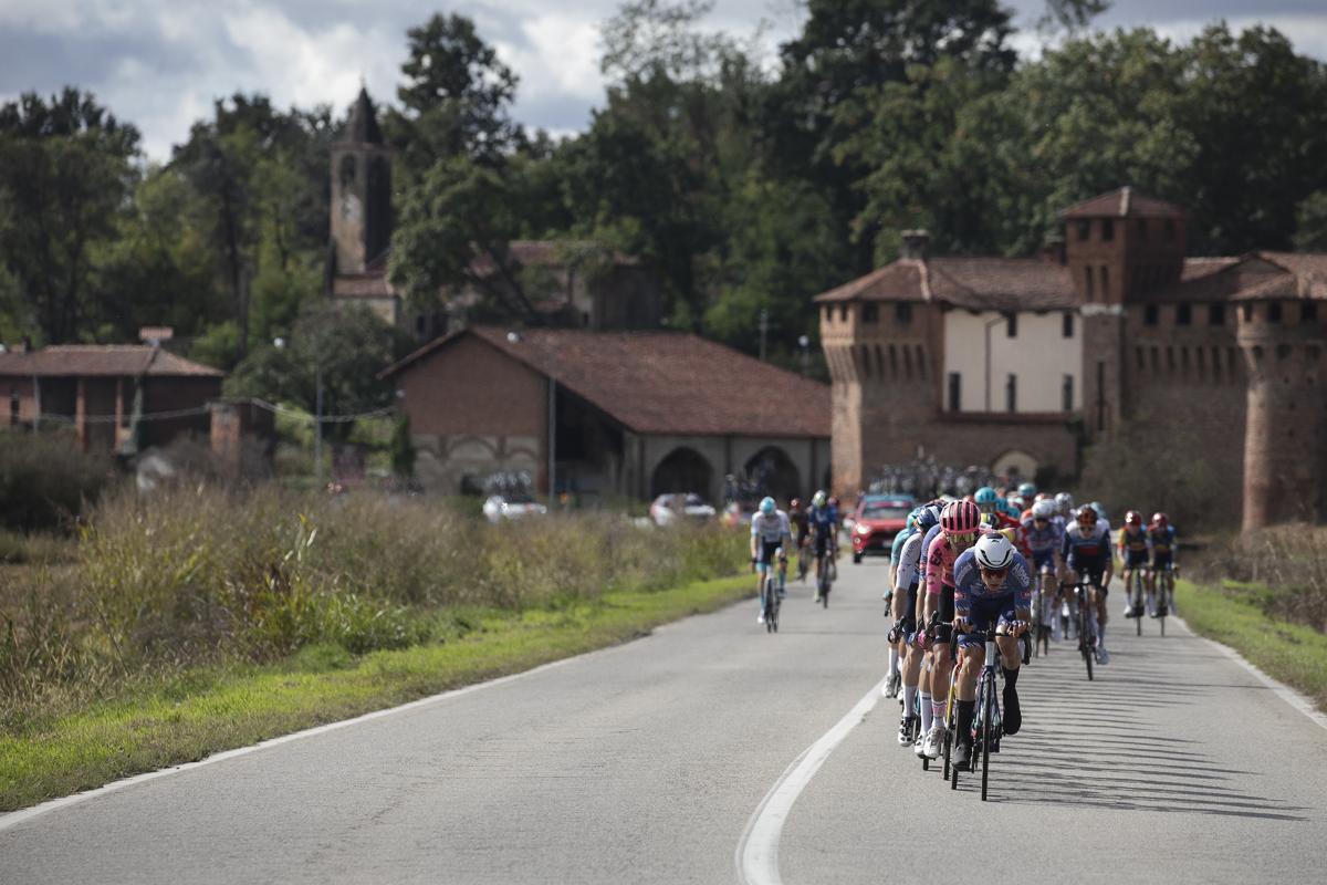 Gran Piemonte 2024 - A group of riders head down the road with the impressive Castello di Proh and a village church tower as the backdrop