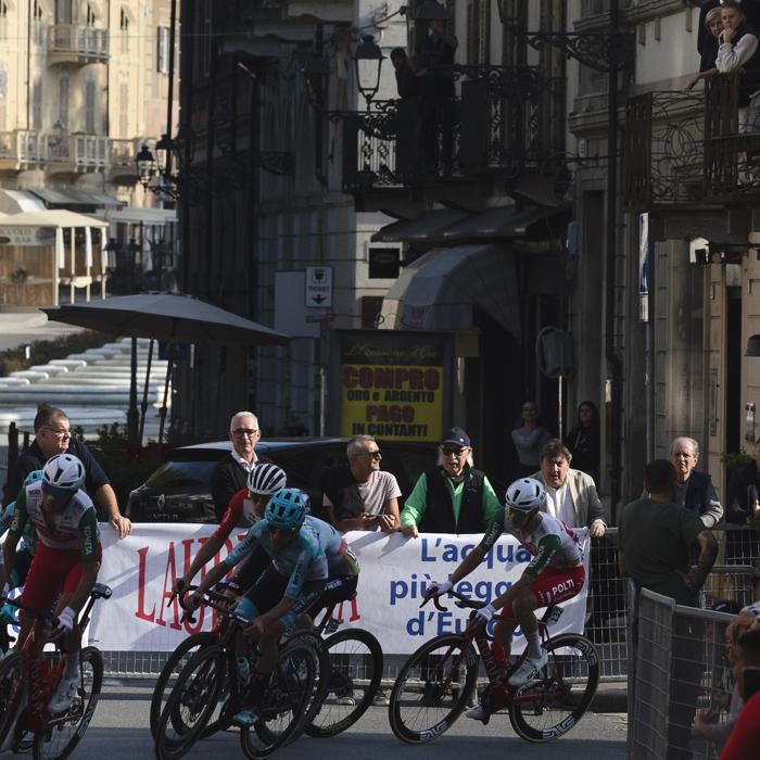Gran Piemonte 2025 - A group of riders round a corner in Acqui Terme