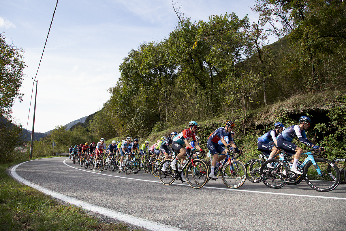 Il Lombardia 2024 - Riders climb past caves with hills in the background in Dosso