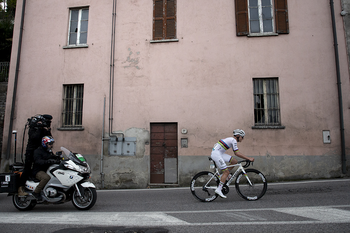 Il Lombardia 2024 - Tadej Pogačar rides past a pastel pink building in Como
