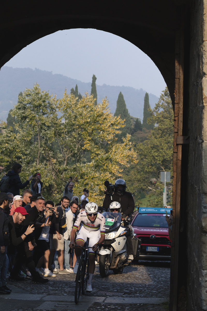 Il Lombardia 2025 - Tadej Pogačar is illuminated by late afternoon sunlight as he passes through the ancient gateway of Porta San Lorenzo