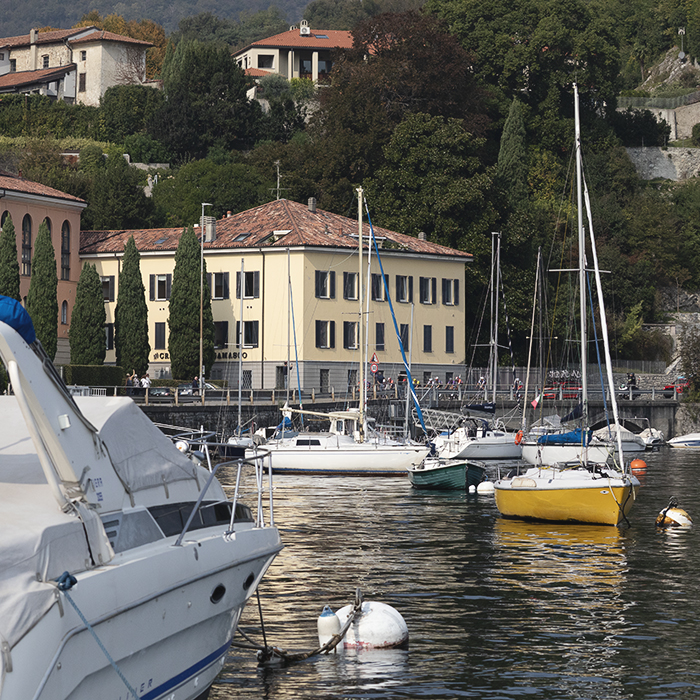 Il Lombardia 2025 - The breakaway viewed across boats moored on the Lago di Lecco