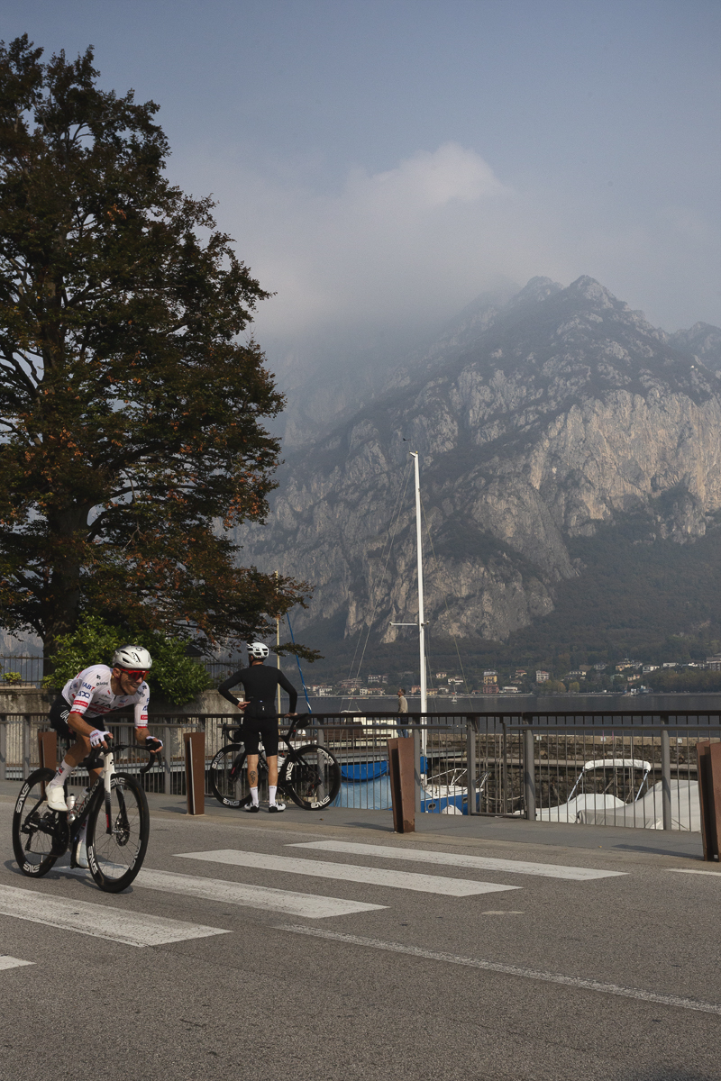 Il Lombardia 2025 - Rafał Majka races past Lago di Lecco with beautiful mountains as a backdrop