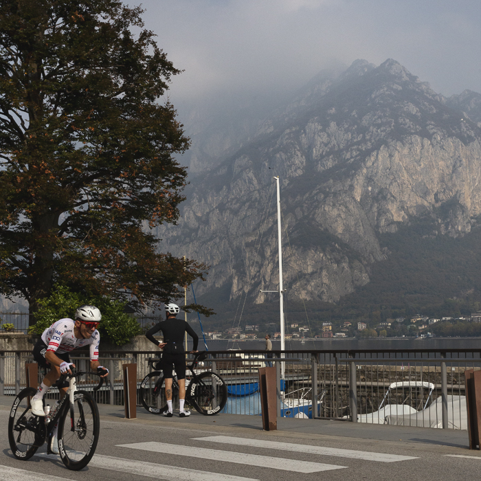 Il Lombardia 2025 - Rafał Majka races past Lago di Lecco with beautiful mountains as a backdrop